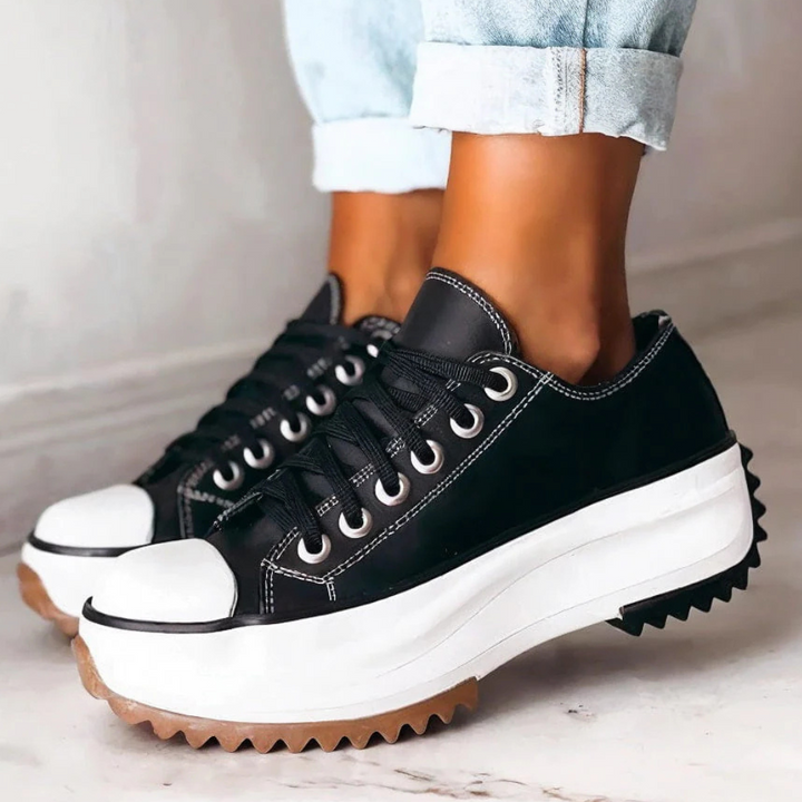 Schwarze Plateau-Sneaker aus Leder, Damen, modisch, lässig, robuste Sohle, Jeanshintergrund.