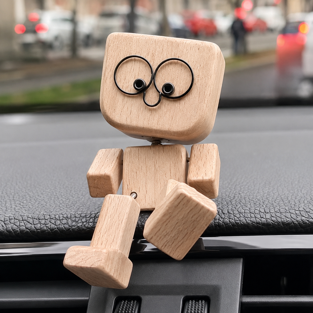 Sedící dřevěná figurka s kulatými brýlovými očima na palubní desce auta, nohy visí přes okraj. 1