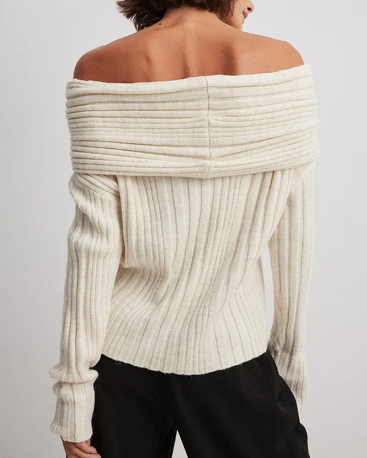 Frau trägt cremeweißen, schulterfreien Strickpullover, geripptes Design, modisch, elegant.