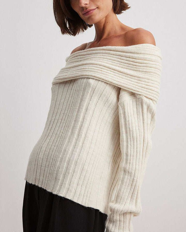 Frau trägt cremeweißen, schulterfreien Strickpullover, modisch, elegant, Herbstmode.