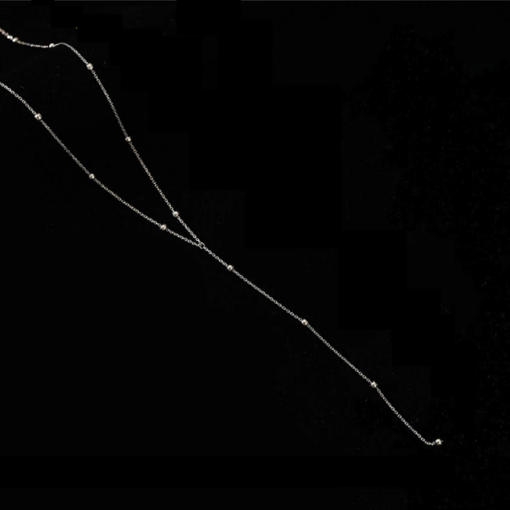 Silberne Halskette mit Perlen, elegantes Schmuckstück, minimalistisches Design auf schwarzem Hintergrund.