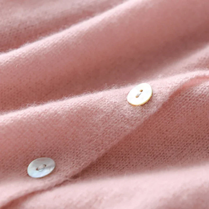 Rosa Kaschmirpullover mit Perlmuttknöpfen, weiches Material, luxuriöse Damenmode.