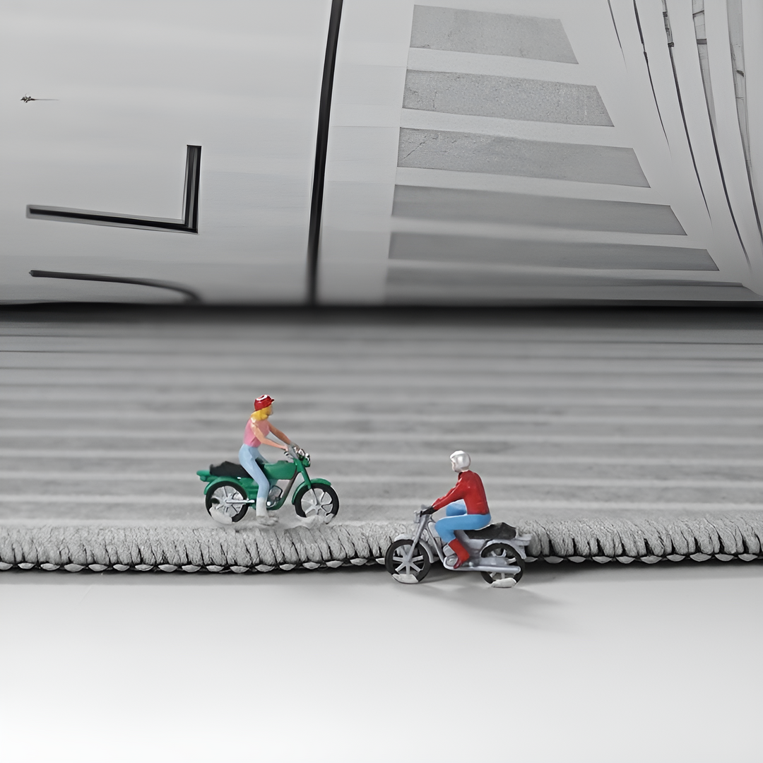 Zwei Miniaturfiguren auf Motorrädern auf grauer, strukturierter Oberfläche.