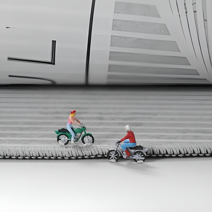 Zwei Miniaturfiguren auf Motorrädern auf grauer, strukturierter Oberfläche.
