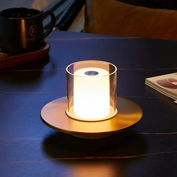 Moderne LED-Tischlampe, goldfarben, zylindrisch, auf dunklem Tisch, stimmungsvolle Beleuchtung.