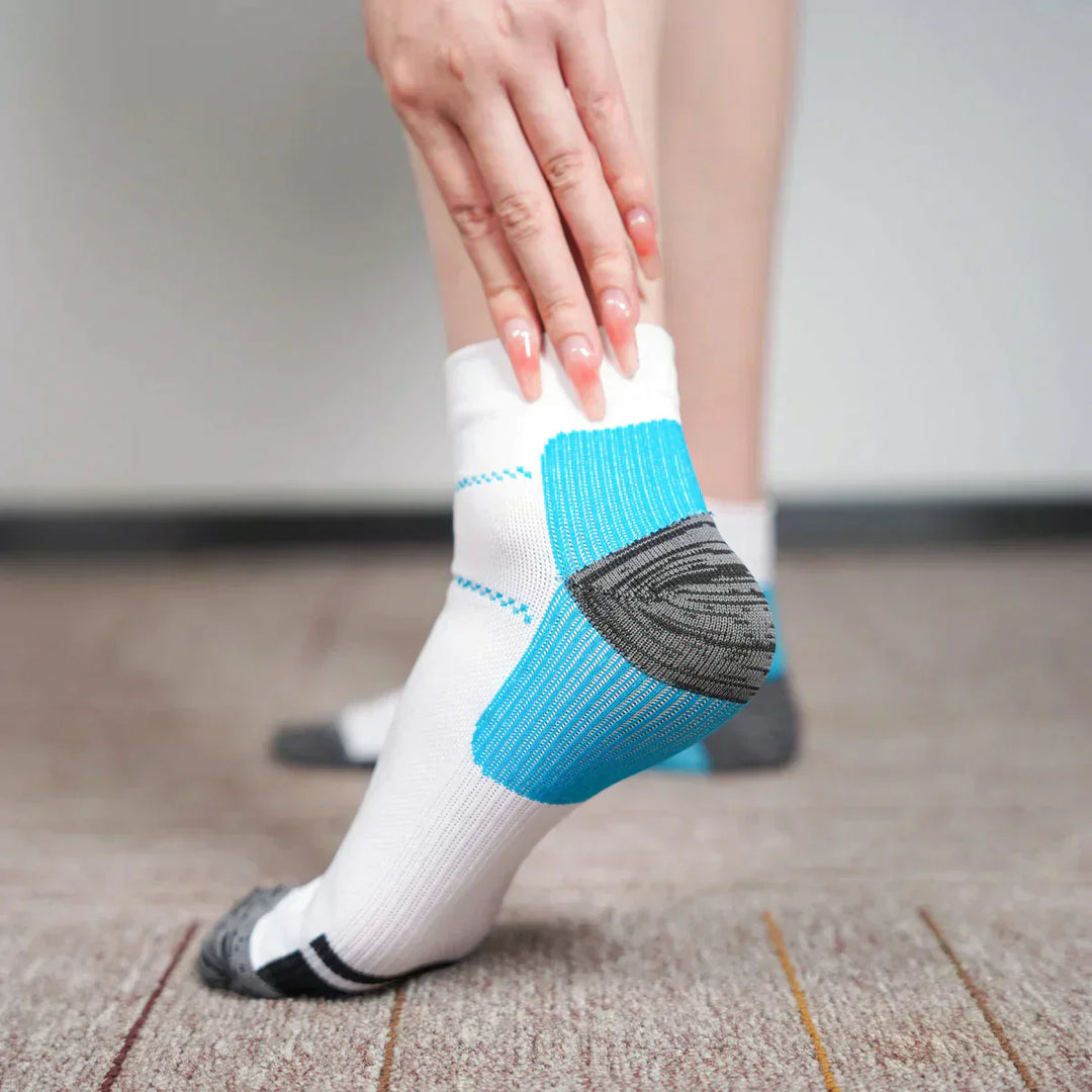 Weiße Sportsocken mit blauen und grauen Akzenten, getragen auf Teppichboden.