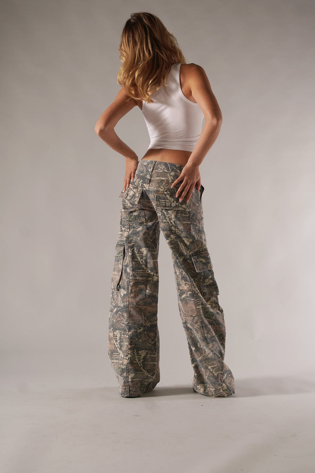 Frau in weißem Tanktop und Camouflage-Cargohose, Mode, Freizeitkleidung, Rückansicht.