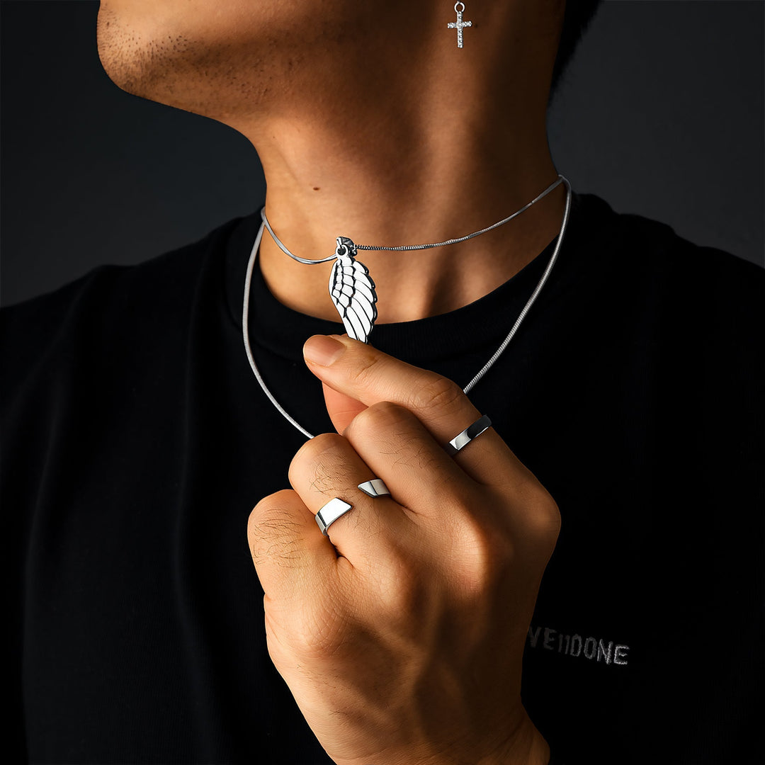 Mann mit silbernem Engelsflügel-Anhänger, Kreuz-Ohrring und Ringen, modisches Schmuckset.