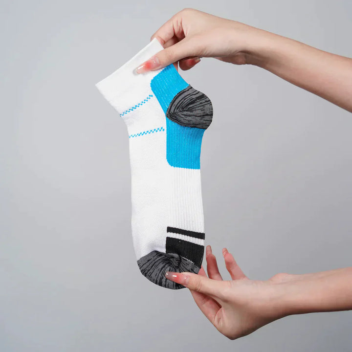 Weiße Sportsocke mit blauem und grauem Akzent, in Hand gehalten, auf grauem Hintergrund.