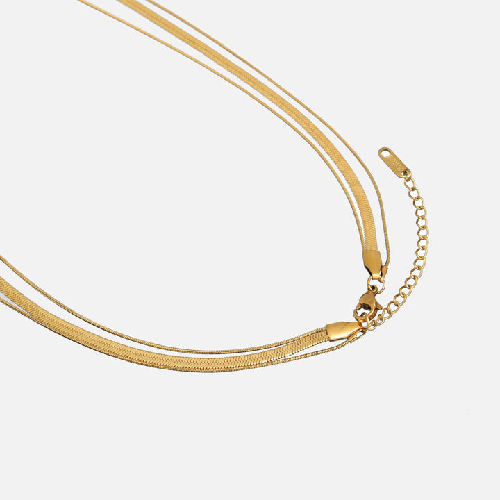 Detail karabinky a prodlužovacího řetízku zlatého náhrdelníku na světlém pozadí 2