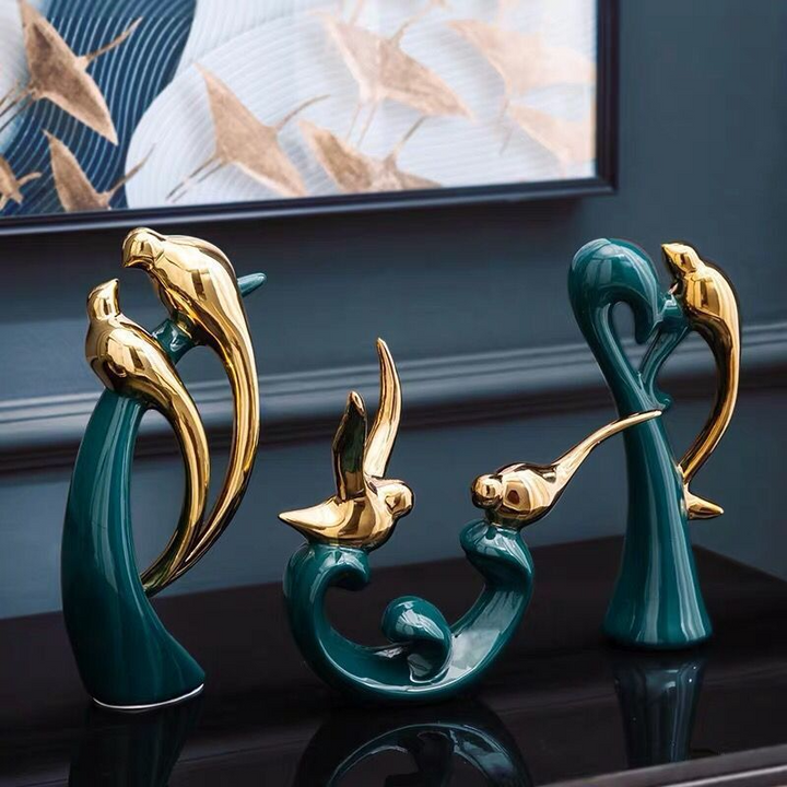 Goldene und grüne Vogelskulpturen aus Keramik auf schwarzem Tisch, moderne Wohnkultur.