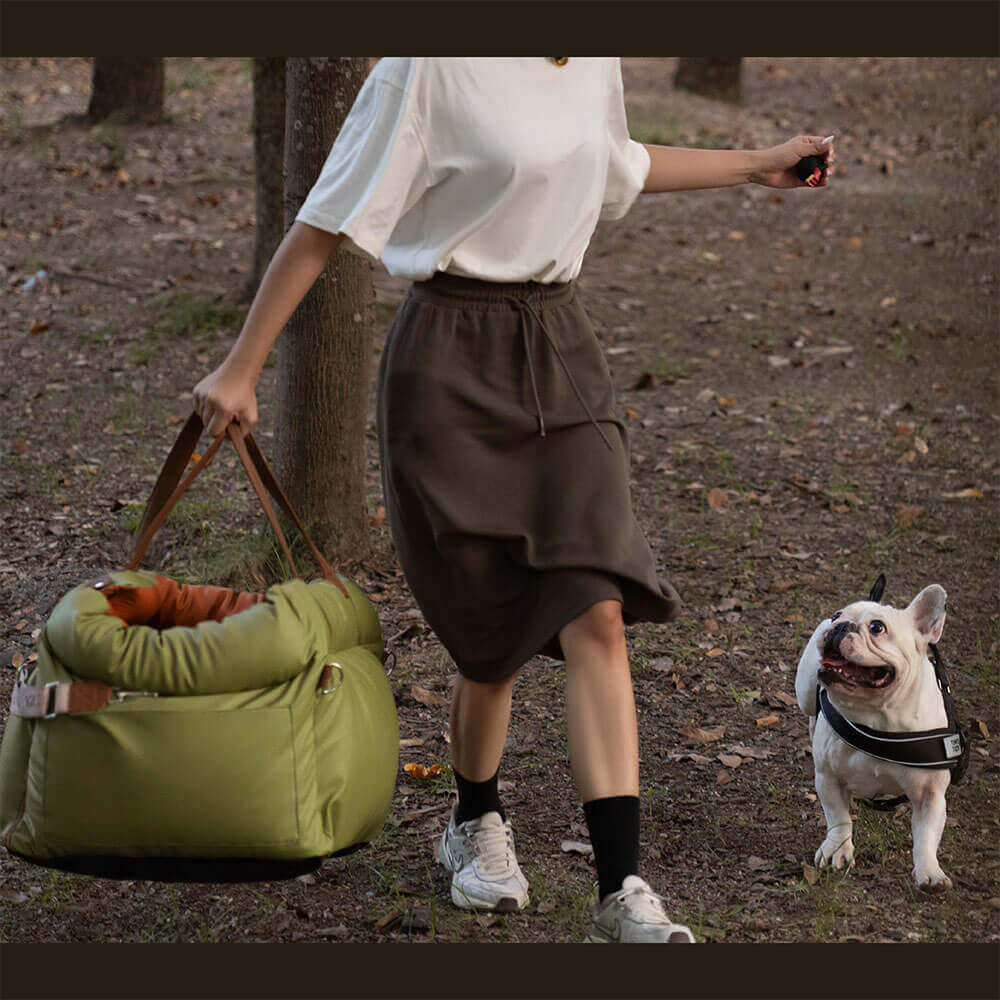 Frau mit grünem Hundebett aus Kunstleder und Bulldogge im Wald spazieren.