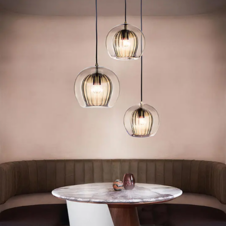 Drei moderne Glas-Pendelleuchten über rundem Marmortisch in elegantem Esszimmer.