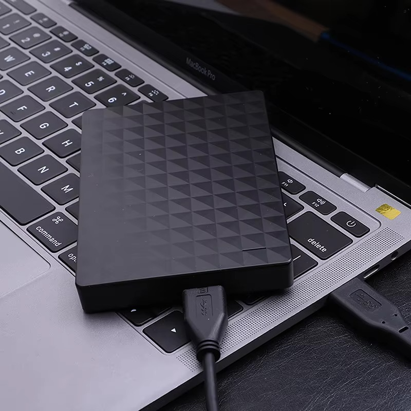 Disk položený na klávesnici notebooku, k němu připojený černý USB kabel 3