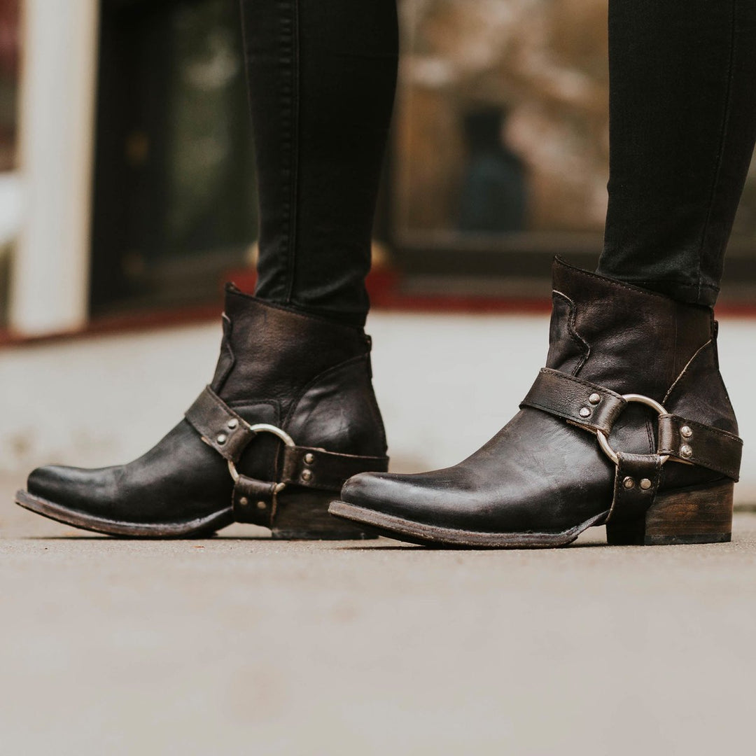 Schwarze Lederstiefeletten mit Schnallen, Damenmode, lässiger Stil, Straßenhintergrund.