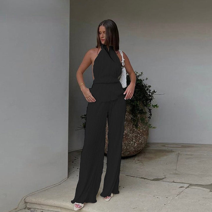 Frau in schwarzem ärmellosen Jumpsuit, elegante Mode, Sommeroutfit, vor modernem Gebäude.