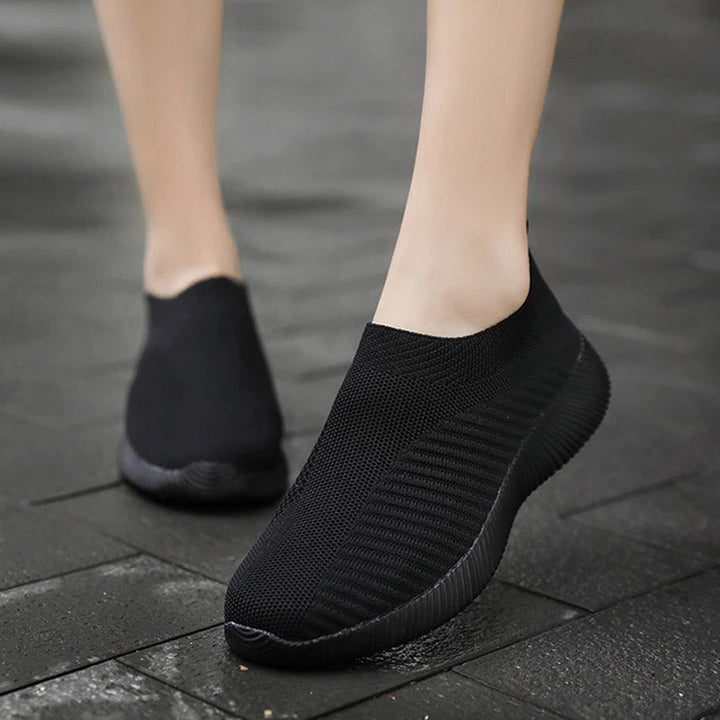 Schwarze Sneaker ohne Schnürsenkel, atmungsaktiv, rutschfest, für Damen, auf nassem Pflaster.