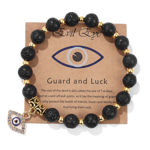 Schwarzes Natursteinarmband mit türkischem Auge, goldenen Perlen und Anhänger auf Karte.