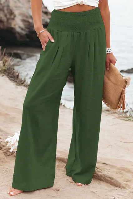 Frau in grüner Leinenhose am Strand, Sommermode, weite Passform, lässiger Stil.