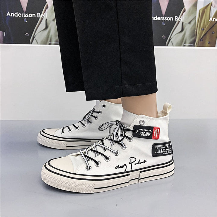 Weiße High-Top-Sneaker mit schwarzer Schrift, lässiger Stil, Unisex, modisch.