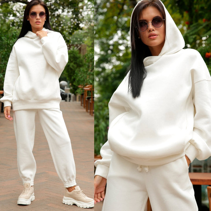 Frau in weißem Hoodie und Jogginghose, Sonnenbrille, lässiger Look, Outdoor-Hintergrund.
