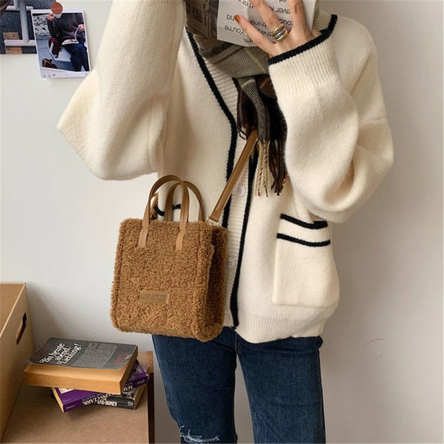 Frau mit weißer Strickjacke, brauner Plüschhandtasche, Jeans, modisch, lässig.