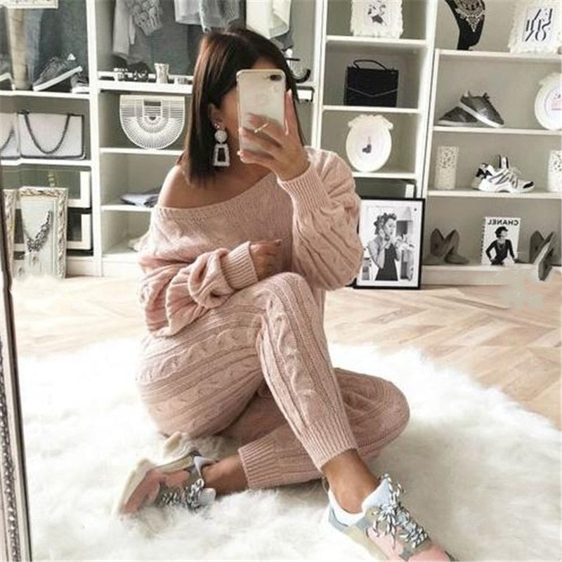 Frau in rosa Strickpullover und Jogginghose, sitzt auf Teppich, modische Sneakers, Spiegel-Selfie.