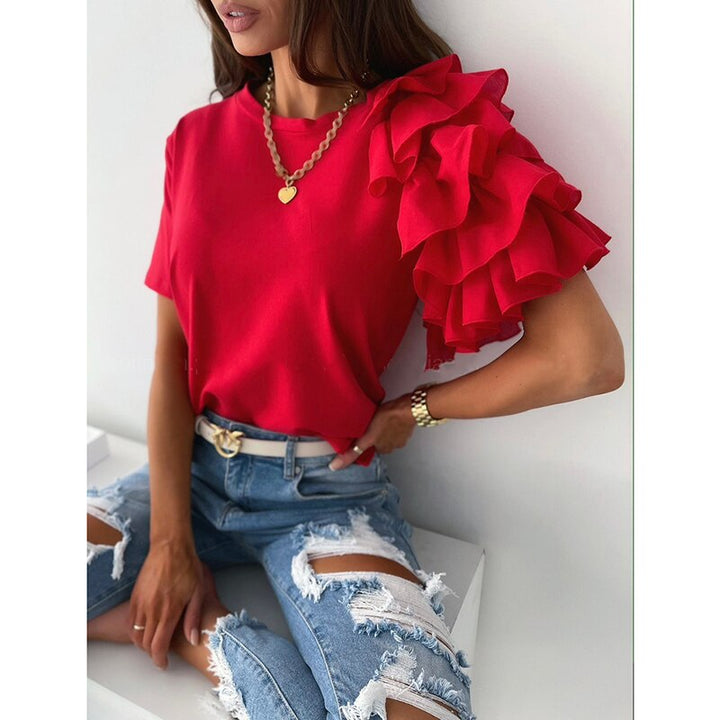 Frau in rotem Rüschen-Top, zerrissene Jeans, goldene Halskette, modisches Outfit.