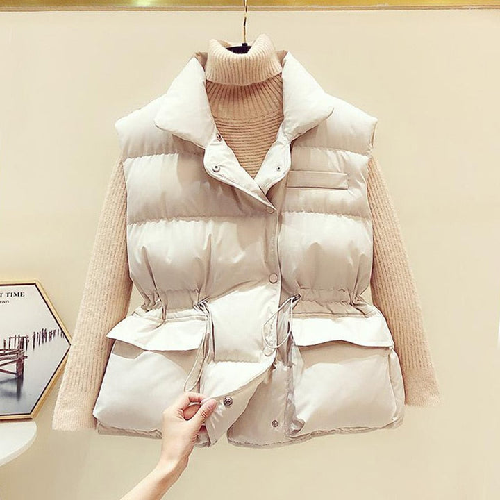 Weiße Daunenweste Damen, ärmellos, mit Taschen, über beigem Rollkragenpullover.