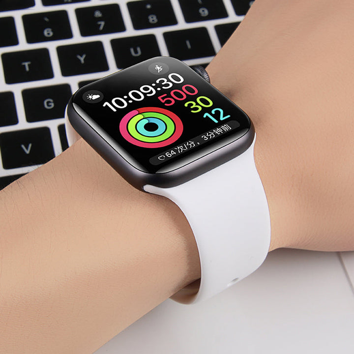 Smartwatch mit weißem Armband, Fitness-Tracker, auf Handgelenk vor Laptop-Tastatur.