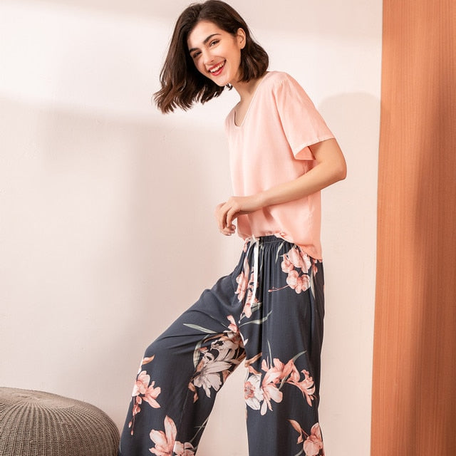 Frau in rosa T-Shirt und blumiger Hose, lächelnd, moderne Freizeitmode, Innenraum.