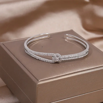 Silbernes Armband mit Strasssteinen auf beigem Hintergrund, eleganter Schmuck für Damen.