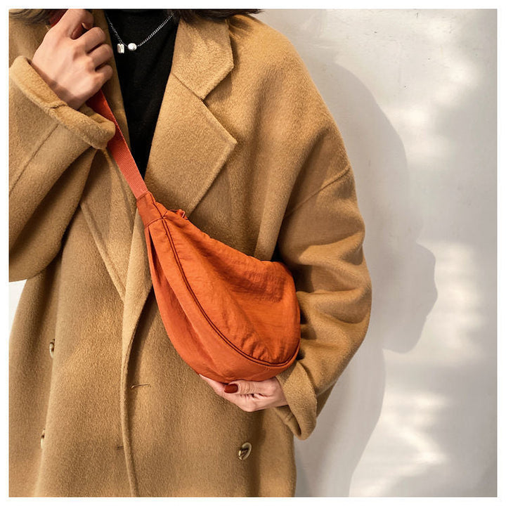 Frau mit braunem Mantel und orangefarbener Umhängetasche aus Stoff, modisch, Herbstmode.
