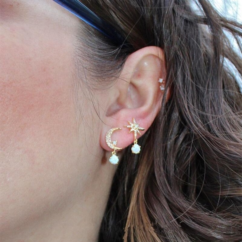 Goldene Ohrringe Mond und Stern mit Perlen, Damenmode, eleganter Schmuck, Nahaufnahme.