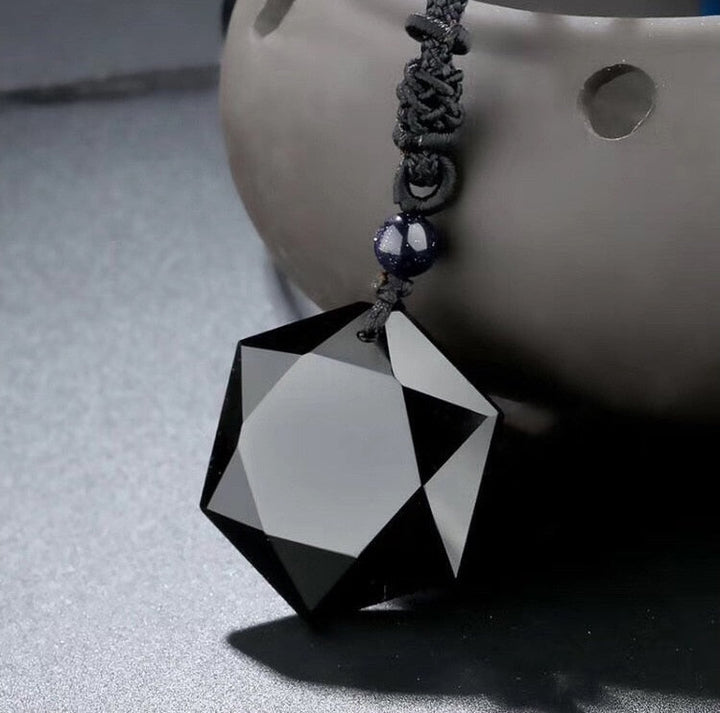 Schwarzer Kristallanhänger, facettiert, geometrisch, an schwarzer Kordel, eleganter Schmuck.