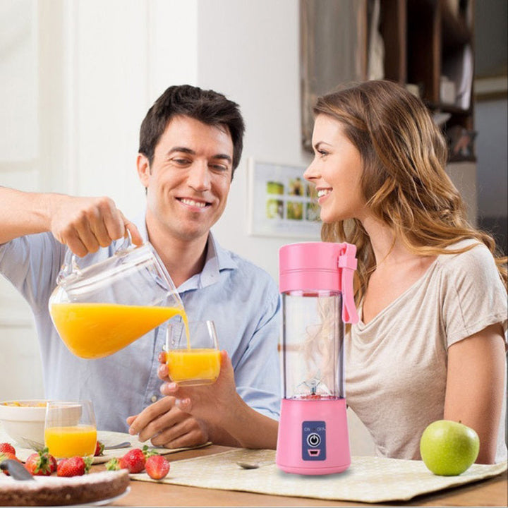 Pinker tragbarer Mixer auf Küchentisch, ideal für Smoothies, mit Obst und Saft, modernes Design.