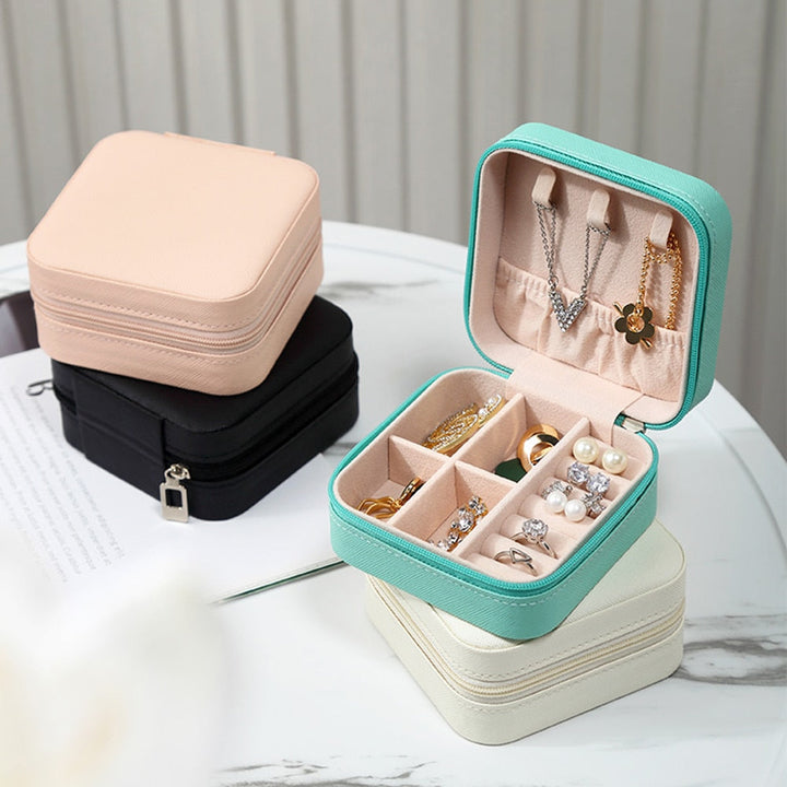 Türkisfarbene Schmuckbox mit Fächern, ideal für Ringe und Ohrringe, auf Tisch.
