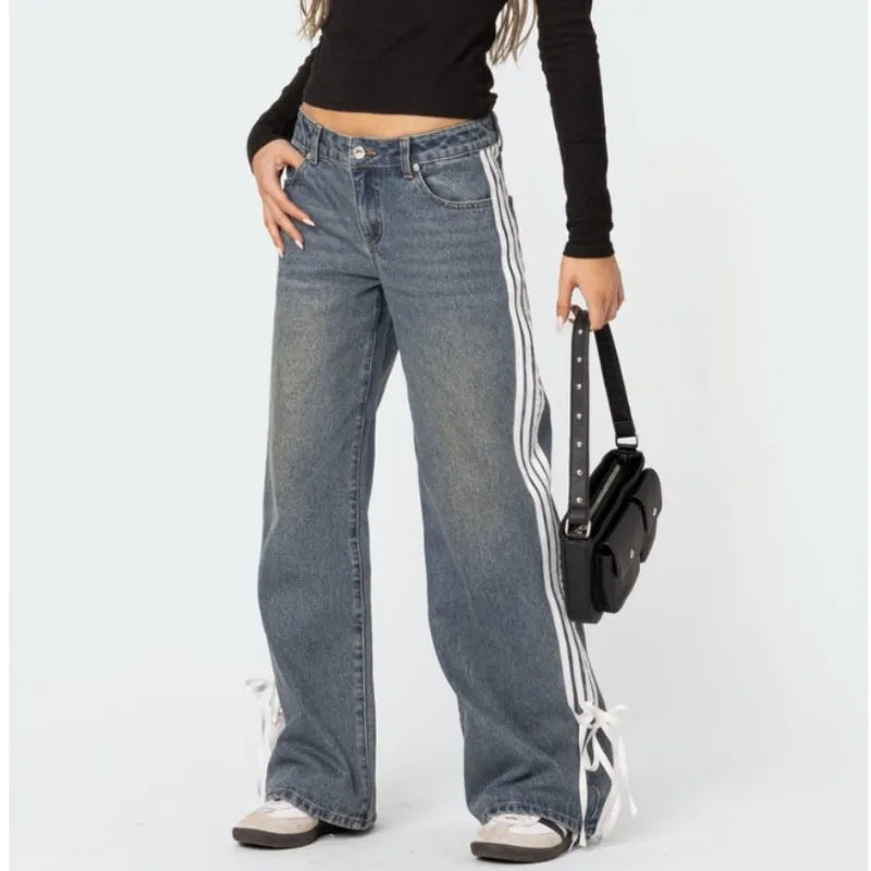 Frau in blauen Y2K-Jeans mit weitem Bein, Seitenstreifen und Schnürdesign, schwarze Tasche.
