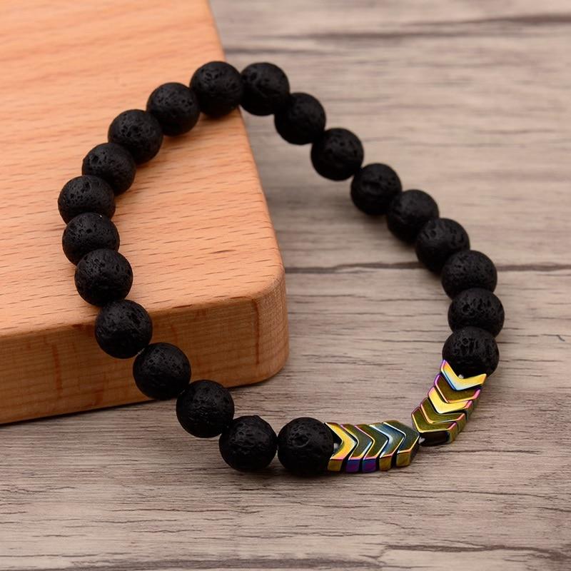 Schwarzes Lavastein-Armband mit bunten Pfeil-Perlen, elastisch, Unisex-Schmuck, Holzuntergrund.