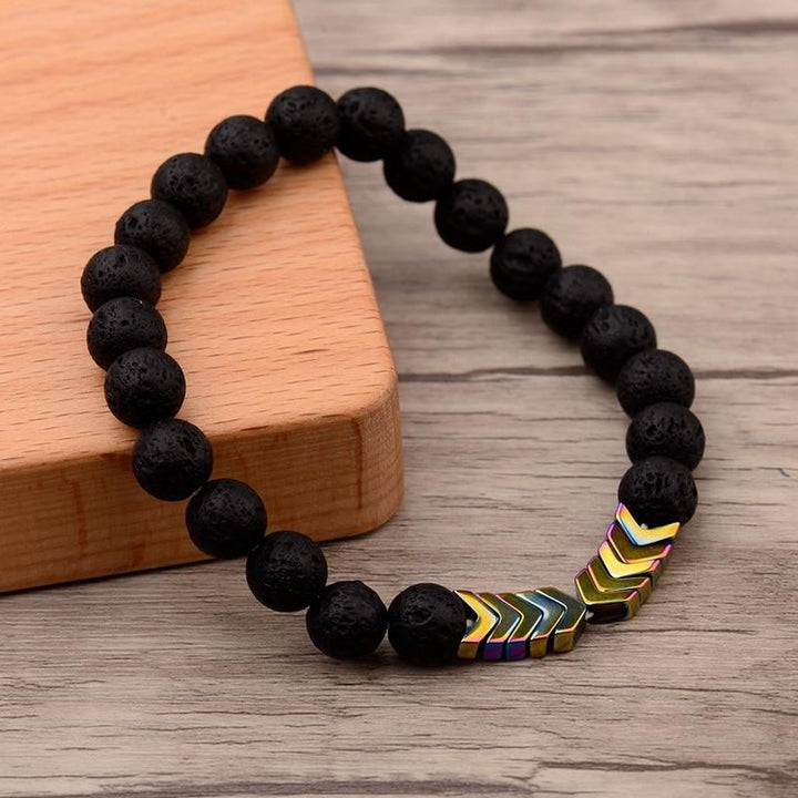 Schwarzes Lavastein-Armband mit bunten Pfeil-Perlen, elastisch, Unisex-Schmuck, Holzuntergrund.