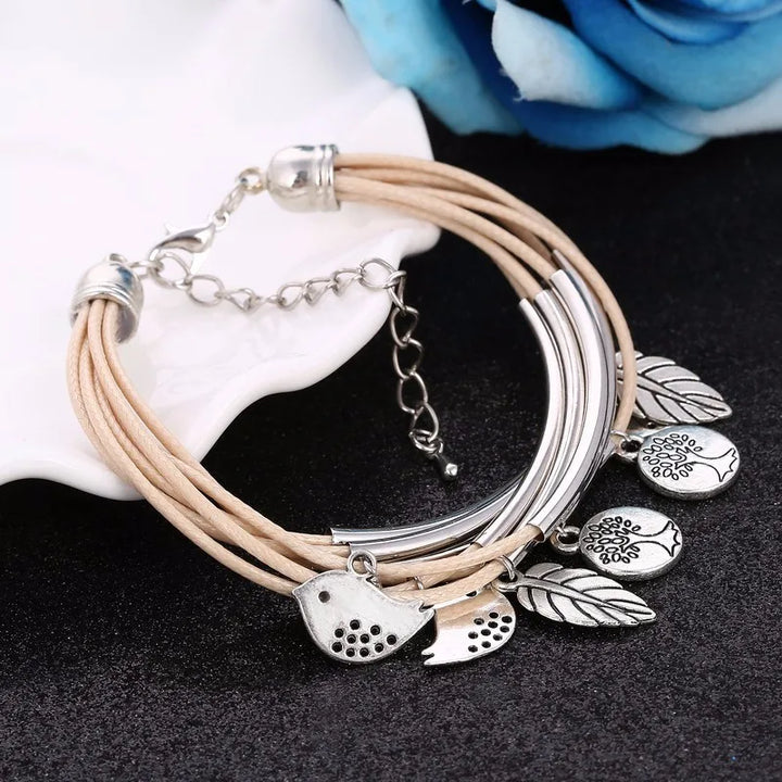 Beiges Lederarmband mit silbernen Anhängern, Blatt- und Vogelmotiv, Damenmode-Schmuck.
