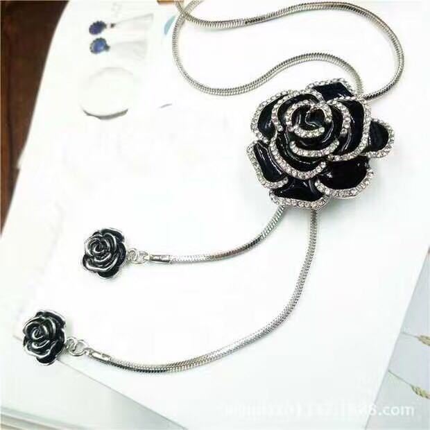 Schwarze Rosenbrosche mit Strass, elegantes Schmuckstück, silberne Kette, modisches Accessoire.