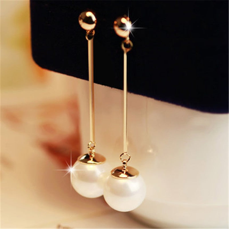 Goldene Ohrringe mit langen Stäben und weißen Perlen, eleganter Schmuck für Damen.