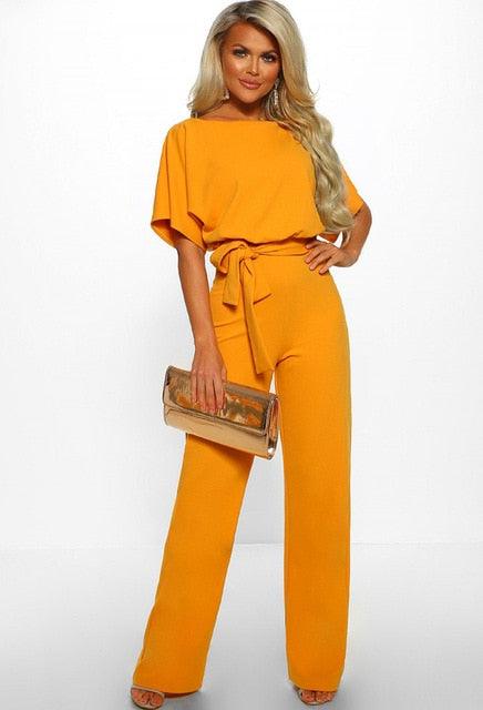 Frau in gelbem Jumpsuit mit Gürtel, goldene Clutch, elegante Mode, Abendoutfit, Damenbekleidung.