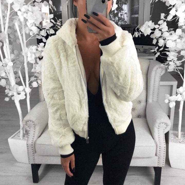 Frau in weißer Kunstpelzjacke, schwarzer Overall, modernes Wohnzimmer, stilvolle Mode.