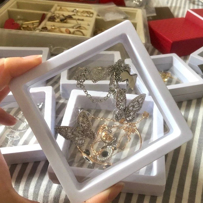 Schmuckdisplay mit Schmetterlingsanhänger, silber, in weißem Rahmen, auf gestreiftem Hintergrund.