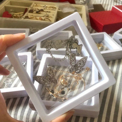 Schmuckdisplay mit Schmetterlingsanhänger, silber, in weißem Rahmen, auf gestreiftem Hintergrund.