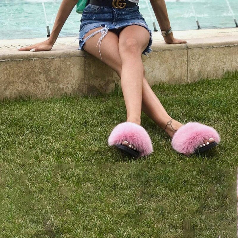 Frau trägt rosa flauschige Hausschuhe, Jeansrock, sitzt im Freien, modisch, Sommermode.