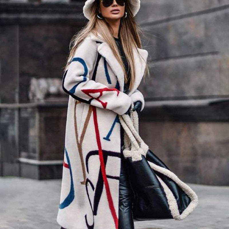 Frau in weißem Mantel mit buntem Muster, schwarzer Tasche und Hut, modisch, urbaner Stil.