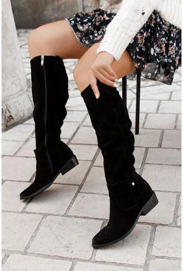 Frau trägt schwarze Wildlederstiefel, kniehoch, mit Absatz, modisch, Herbstmode.